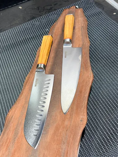 Two premium chef's knives, freshly sharpened, on a timber board