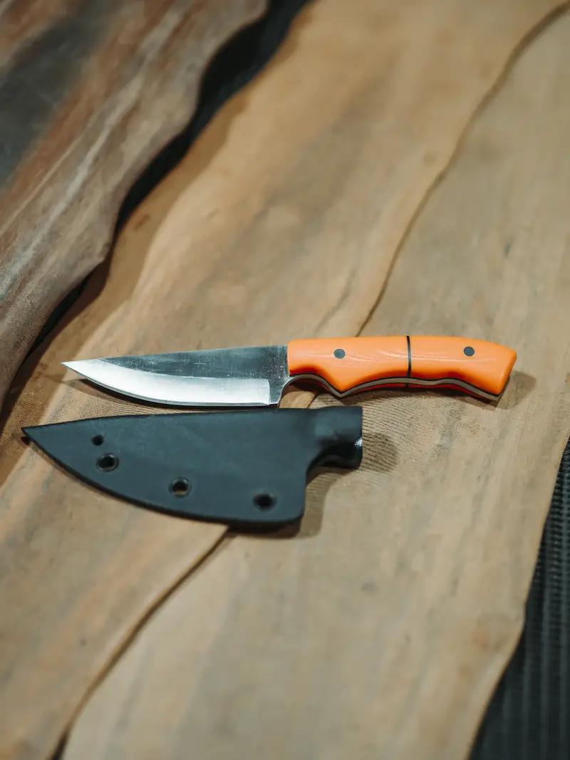 The orange-handled Spiker laid beside the black kydex sheath that was moulded for it